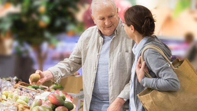 Älterer Mann und jüngere Frau im Supermarkt vor einem Obststand | GettyImages / FredFroese
